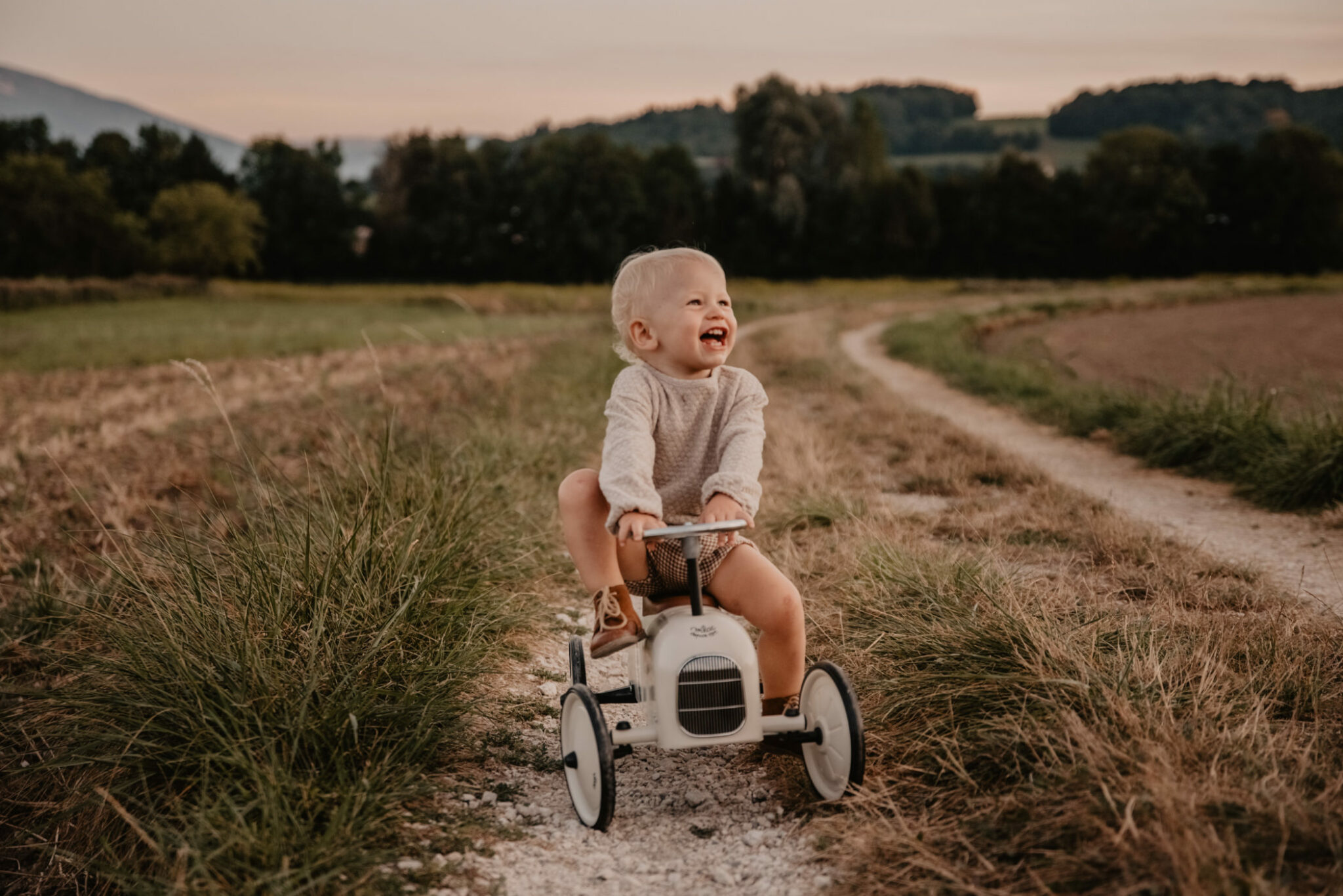 enfant jouant sur sa voiture vintage à pédales